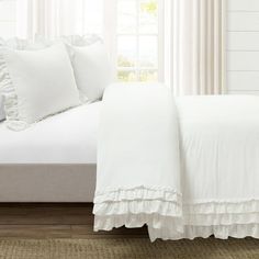 a bed with white sheets and pillows in a room