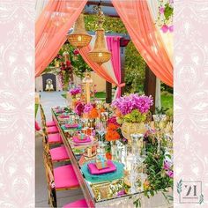 a table set up with pink and gold decor for an outdoor wedding or bridal party