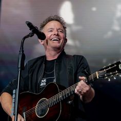 a man holding a guitar and singing into a microphone