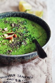 a bowl filled with green soup on top of a table