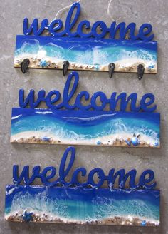 two welcome signs are hanging on the wall with blue and white waves in the background