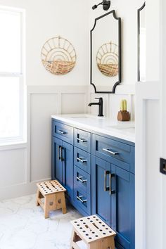 a bathroom with blue cabinets and stools