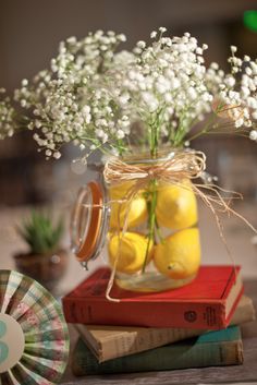 a mason jar filled with lemons and baby's breath on top of books