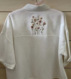 a white shirt with flowers embroidered on it