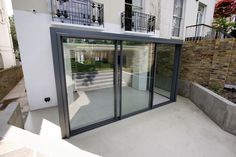 an open glass door on the outside of a building with stairs leading up to it