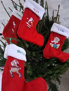 christmas stockings hanging from a tree in front of a brick wall