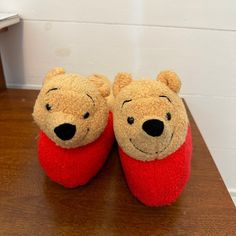 a pair of winnie the pooh slippers sitting on top of a wooden table