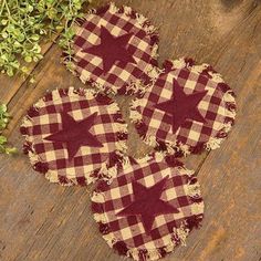 three red and white checkered stars are placed on a wooden surface next to some green plants