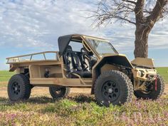 an off - road vehicle parked next to a tree in the middle of a field