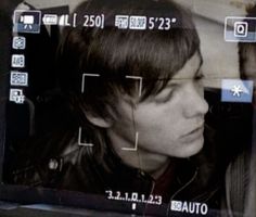 a woman is looking at the screen in front of her face and head, while she's wearing a leather jacket