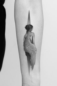 a black and white photo of a woman's leg with an angel wing tattoo on it