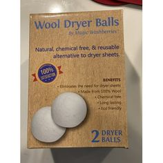 two white wool dryer balls sitting on top of a cardboard package with the box