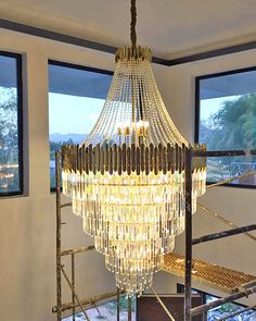 a chandelier hanging from the ceiling in a room with large windows and railings