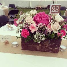 a wooden box filled with lots of pink and white flowers on top of a table