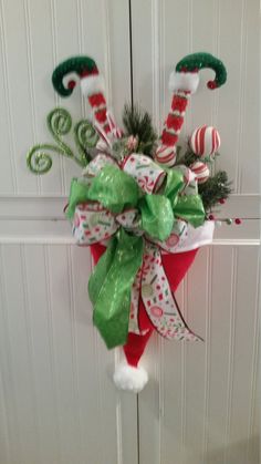 a christmas wreath hanging on the front door decorated with candy canes and holly cones