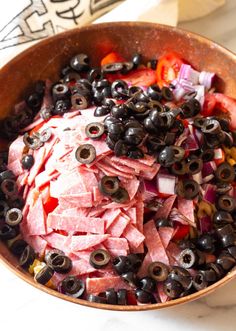 a bowl filled with meat and olives on top of a table