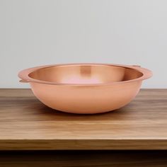 a metal bowl sitting on top of a wooden table