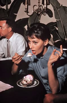 a woman sitting at a table eating cake