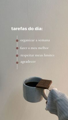 a person is holding a coffee cup and saucer in front of a white wall with the words tarefas do dia on it