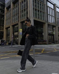 a woman walking down the street in front of some tall buildings