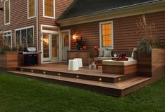 a deck with lights on it next to a house and an outdoor living area in the background