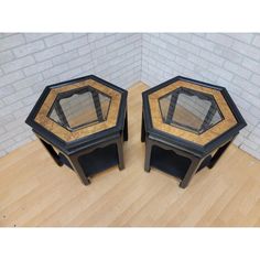 two black and gold side tables sitting on top of a wooden floor