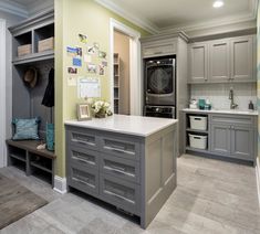 a kitchen with gray cabinets and white counter tops, an oven and washer in the center