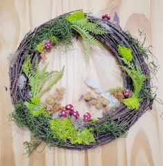 a wreath made out of twigs, ferns and other plants on a wooden table top