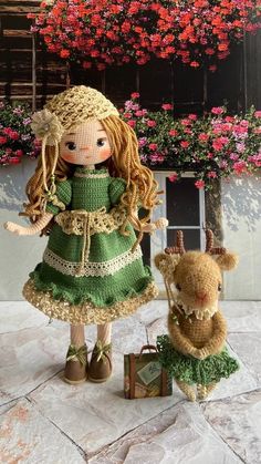 a crocheted doll and her teddy bear are sitting on the ground in front of flowers