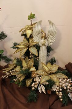 a christmas tree with angel figurines on top of it, surrounded by greenery