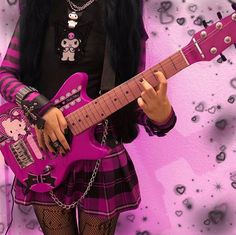 a girl with black hair is holding a pink guitar and posing for the camera in front of a purple background