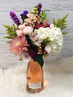 a vase filled with lots of flowers sitting on top of a white fur covered floor