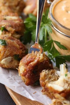 some food is sitting on a plate with a fork and sauce in the jar next to it