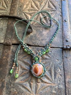 a close up of a piece of jewelry on a wooden surface with beads and chains