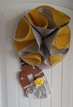 a yellow and silver vase hanging from the side of a white wall next to a pair of shoes