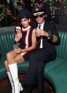 a man and woman dressed in airline uniforms sitting next to each other on a green couch