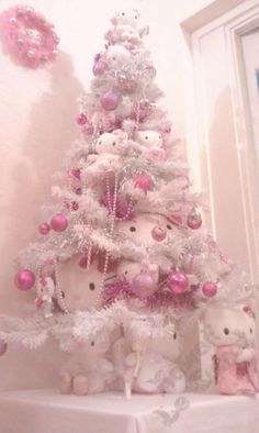 a white christmas tree with pink ornaments and teddy bears on it's sides, in front of a window