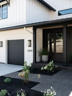 a house with two garages and plants in the front yard