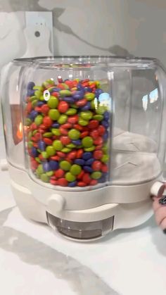 a plastic container filled with lots of colorful candies sitting on top of a counter