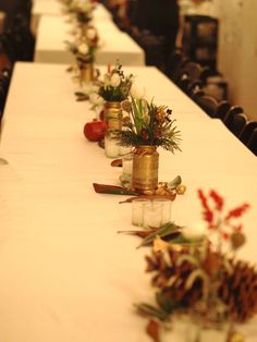 the long table is decorated with pine cones and vases