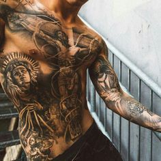 a man with many tattoos on his chest and arm is standing in front of an escalator