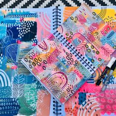 an art journal with pens on top of it next to some colorful papers and markers