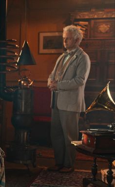 an older man in a suit and tie standing next to a piano with another person looking on