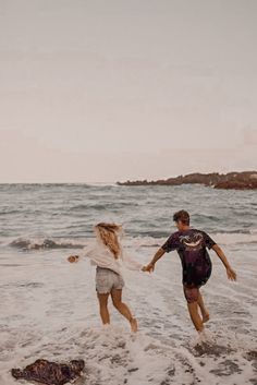 two people are running in the water at the beach