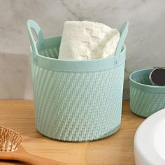 a wooden table topped with two blue baskets filled with towels and a toothbrush next to a sink