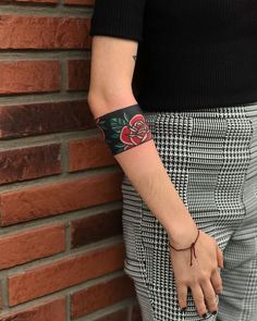 a person with a tattoo on their arm standing next to a brick wall