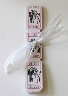 two tickets with ribbons tied to them on a table