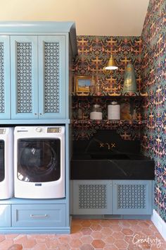 a washer and dryer are in the corner of this laundry room with blue cabinets