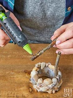 a woman is using a small tool to cut up some rocks on a wooden table