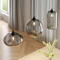 three glass pendant lights hanging from a ceiling in a living room with wood flooring